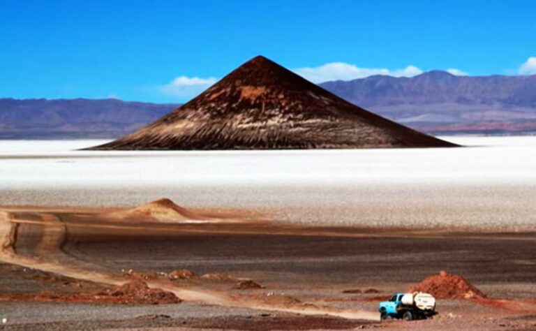 Vista del Cono de Arita, una formación volcánica oscura y simétrica, emergiendo del blanco Salar de Arizaro en la Puna salteña.